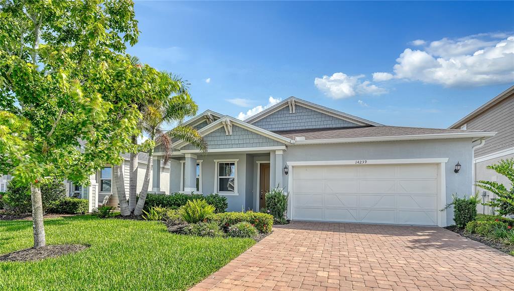 A single-story house with a gray exterior, shingled gables, and a paved driveway — 14239 59TH CIRCLE E, BRADENTON, FL