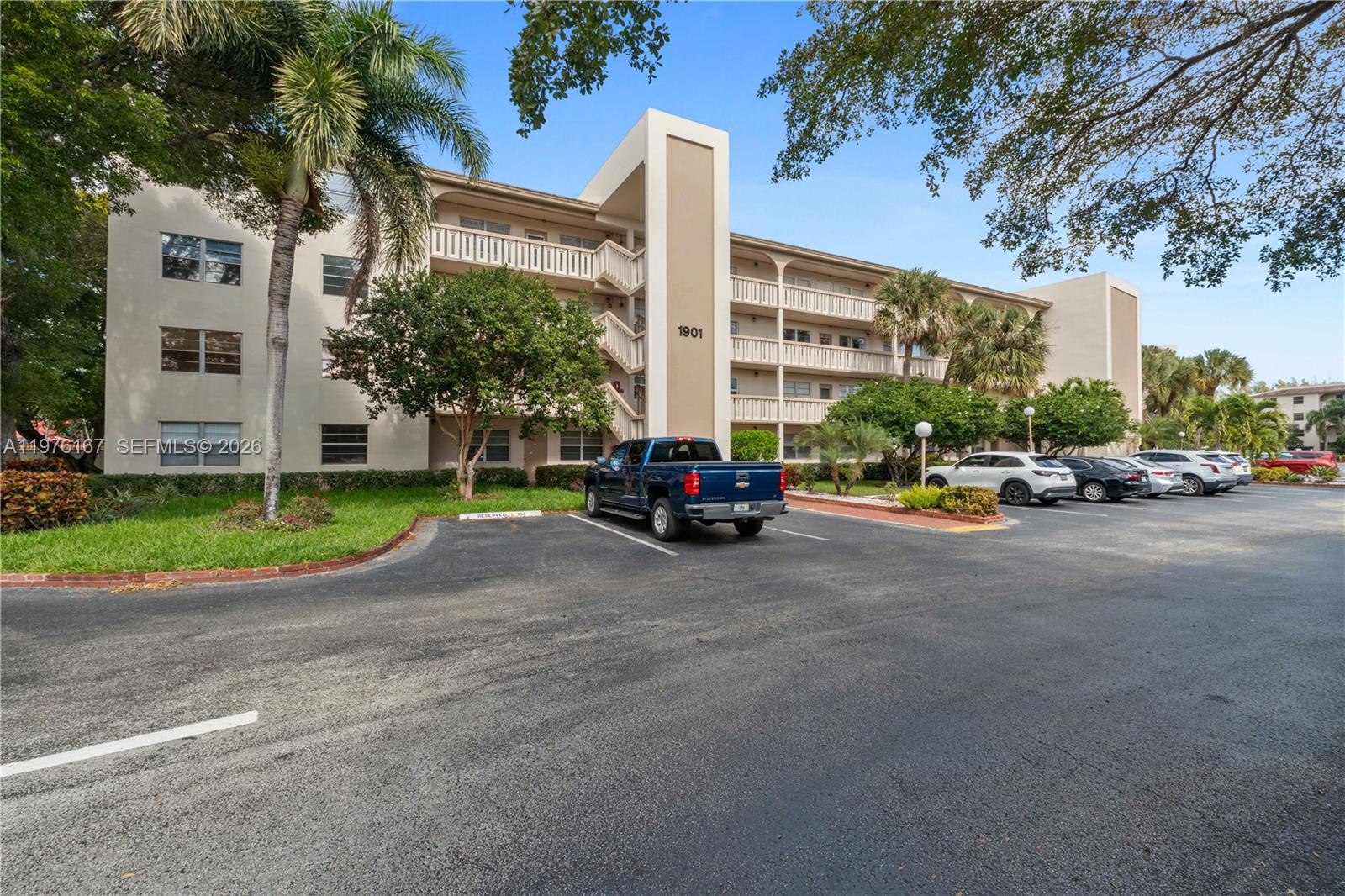 A multi-story apartment building with a parking lot and a blue pickup truck in front — 1901 Bermuda Cir # A1, Coconut Creek FL 33066, COCONUT CREEK, FL