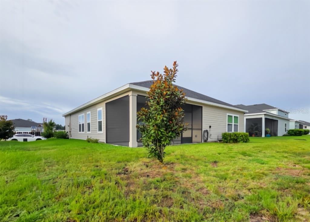 The exterior of a beige single-story house features a screened-in back porch and a small tree — 3294 NE 38TH LANE, OCALA, FL
