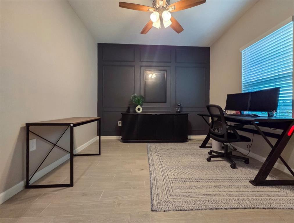 A home office features a dark accent wall with molding, a desk, and tile flooring — 3294 NE 38TH LANE, OCALA, FL