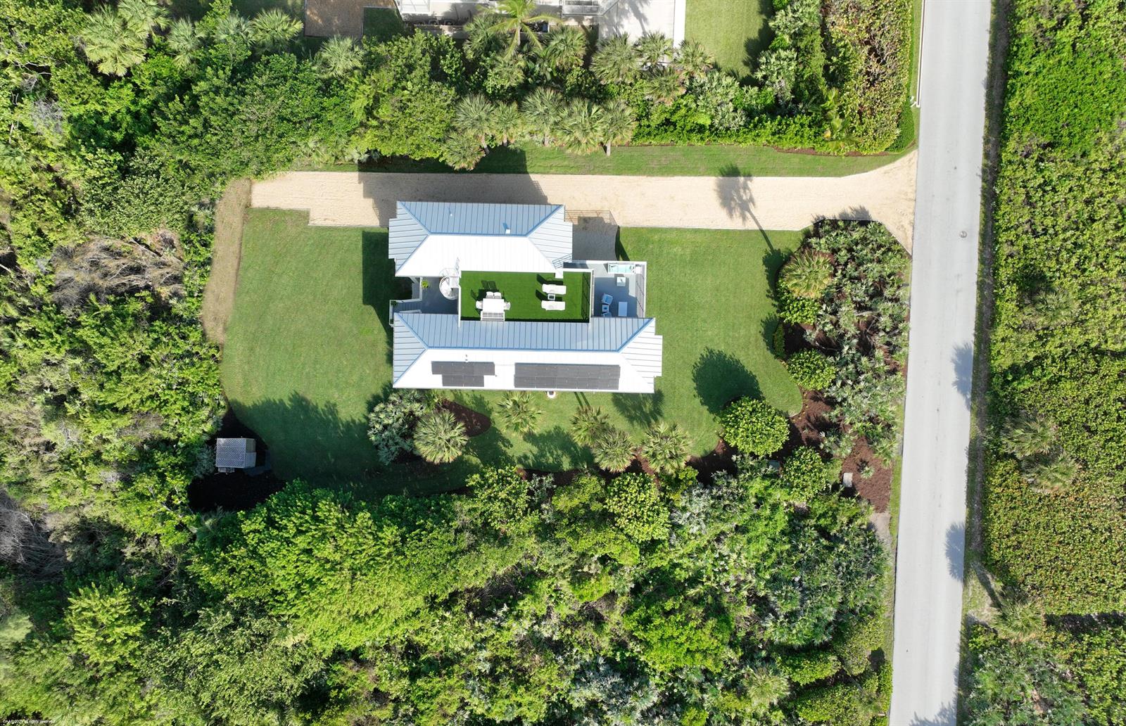 An aerial view of a house with a metal roof, solar panels, and a rooftop terrace — 116 N Beach Road, Jupiter Island FL 33455, JUPITER ISLAND, FL