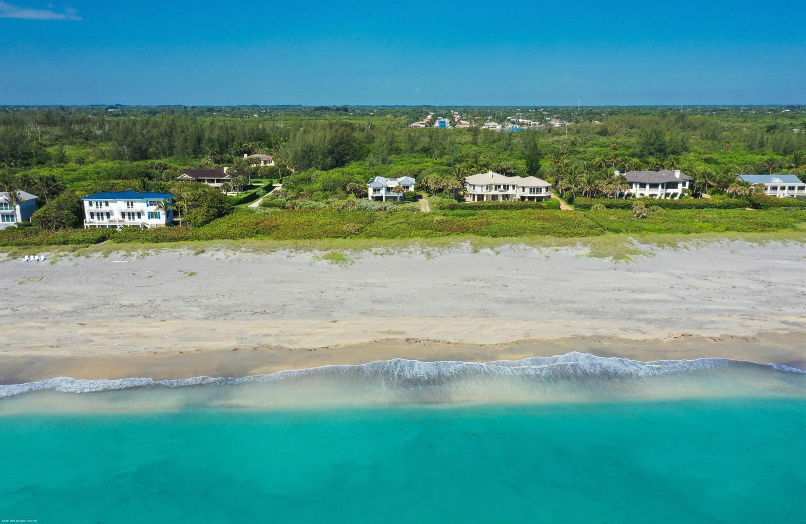 An aerial view shows several beachfront houses nestled along a sandy shore and turquoise ocean — 116 N Beach Road, Jupiter Island FL 33455, JUPITER ISLAND, FL