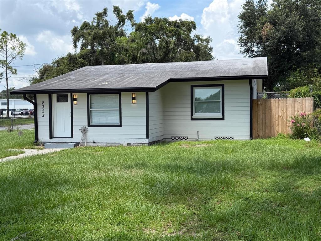 A single-story house with light-colored siding, black trim, and a dark roof sits on grass — 2352 OLD DIXIE HIGHWAY, KISSIMMEE, FL