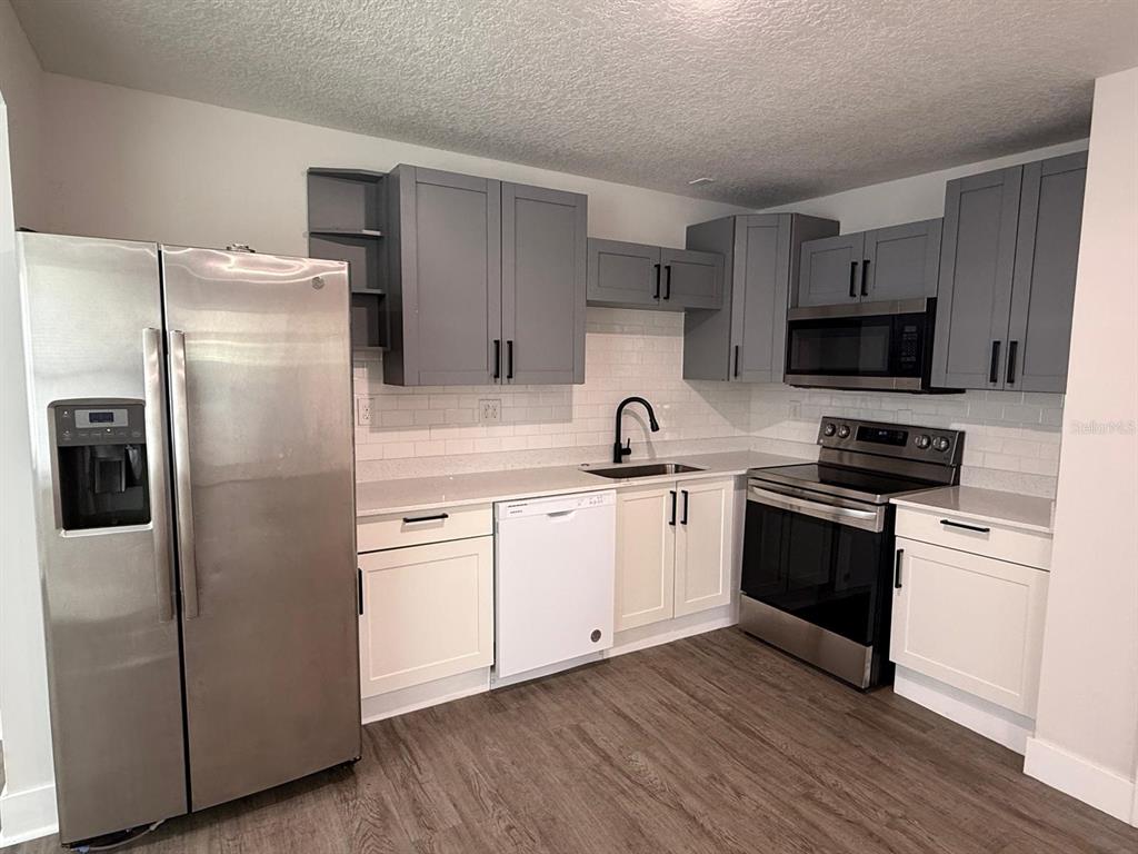 A kitchen features gray upper cabinets, white lower cabinets, stainless steel appliances, and white subway tile — 2352 OLD DIXIE HIGHWAY, KISSIMMEE, FL