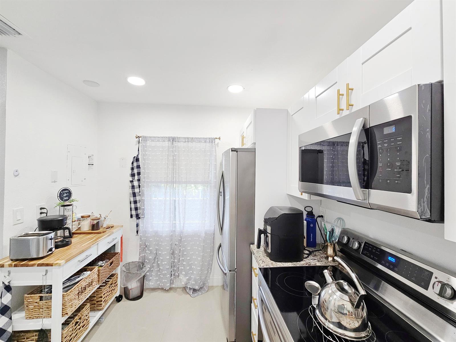 A kitchen features white cabinets, stainless steel appliances, a wooden island, and a window — 7807 Golf Cir Circle # 305, Margate FL 33063, MARGATE, FL