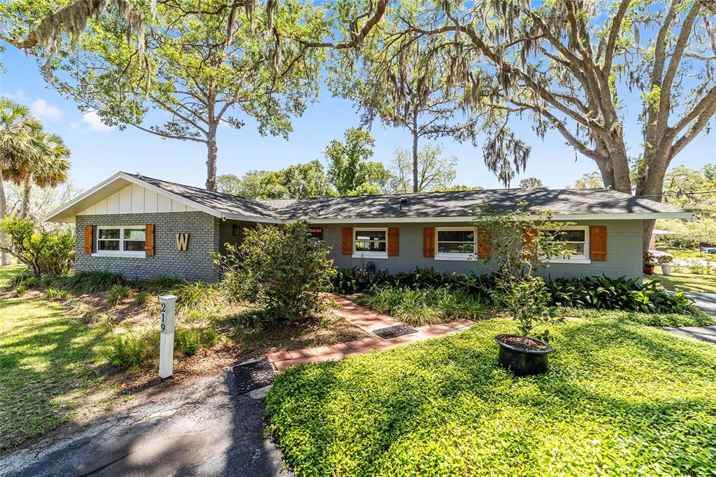 A single-story gray brick house with a shingled roof and wooden shutters — 219 SE 20TH TERRACE, OCALA, FL