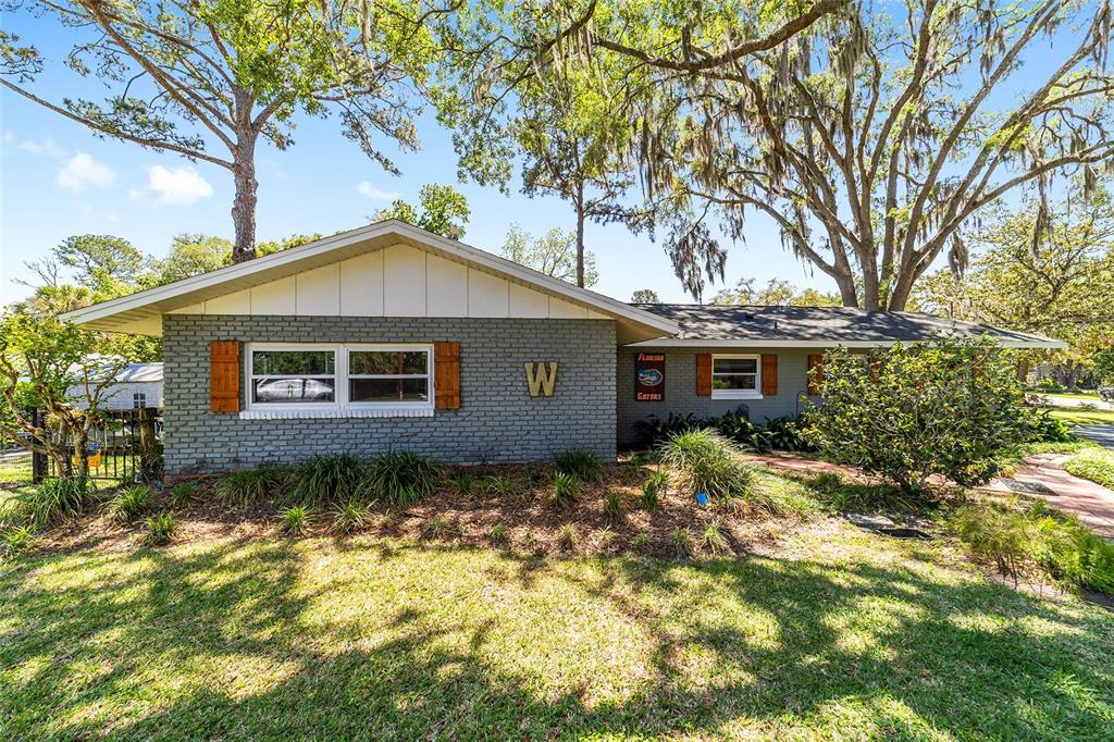 A single-story house with gray brick siding, a white gable, and wooden window shutters — 219 SE 20TH TERRACE, OCALA, FL