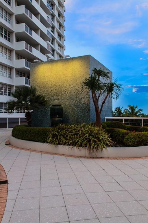 A tall apartment building overlooks a tiled patio with a decorative water feature and landscaping — 100 Lincoln Rd # 943, Miami Beach FL 33139, MIAMI BEACH, FL