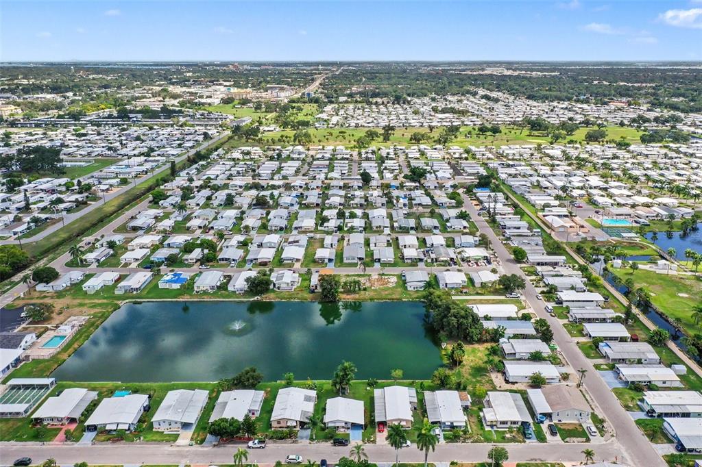 An aerial view shows a dense residential community with many small houses and a pond — 302 51ST AVENUE E, BRADENTON, FL