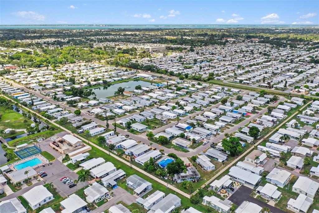 Aerial view of a dense residential community featuring numerous mobile homes and a central pond — 302 51ST AVENUE E, BRADENTON, FL