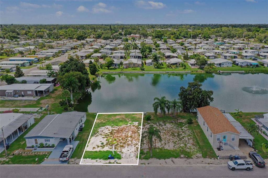 An aerial view shows a vacant waterfront lot outlined in white between two mobile homes — 302 51ST AVENUE E, BRADENTON, FL