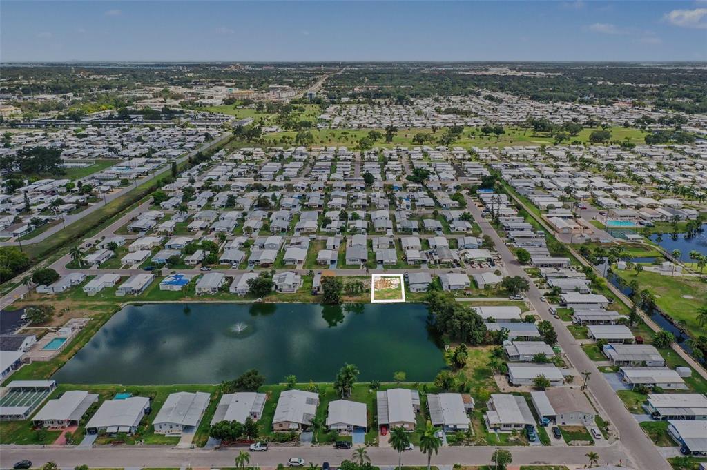 An aerial view of a mobile home community featuring a highlighted vacant lot by a pond — 302 51ST AVENUE E, BRADENTON, FL