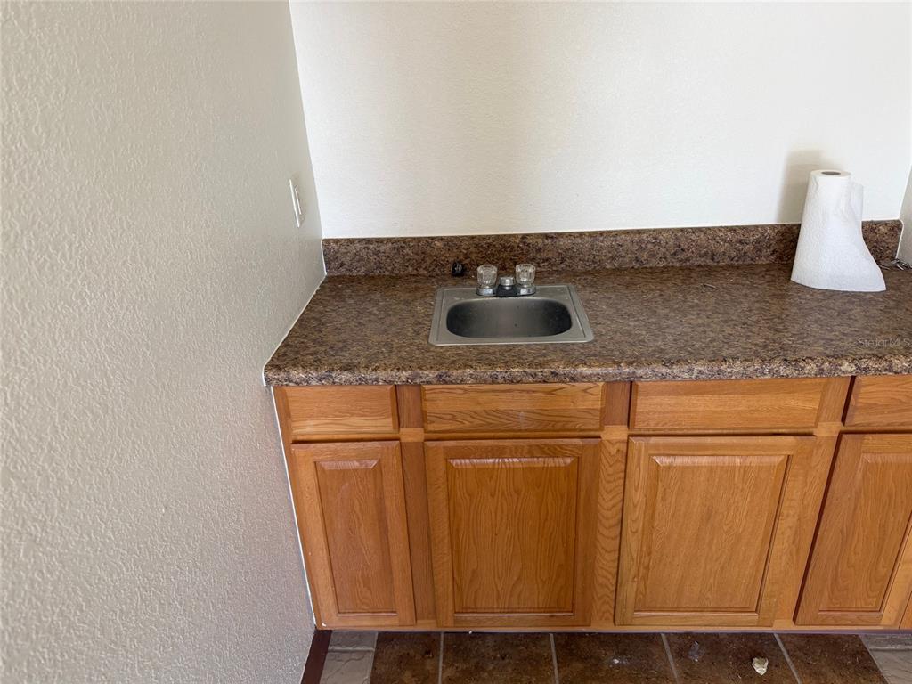 A small kitchen sink is set into a brown laminate countertop above wooden cabinets — 3434 SW 24TH AVENUE UNIT D, GAINESVILLE, FL