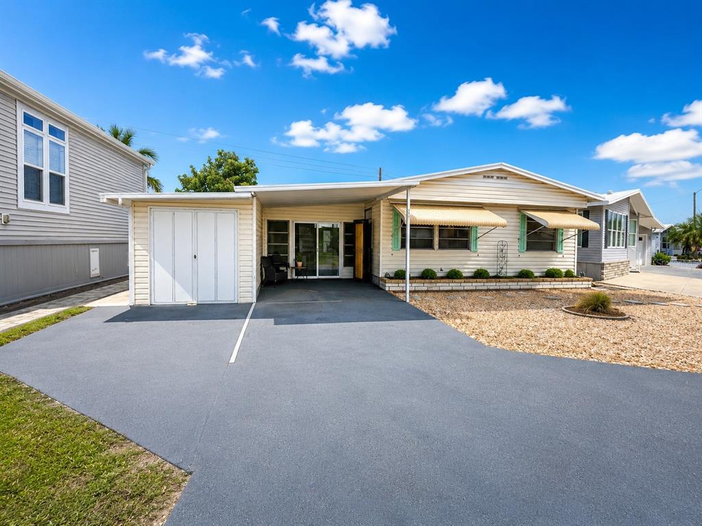 A single-story manufactured home with a carport, gravel landscaping, and a paved driveway — 1912 INDIANA AVENUE, BRADENTON, FL