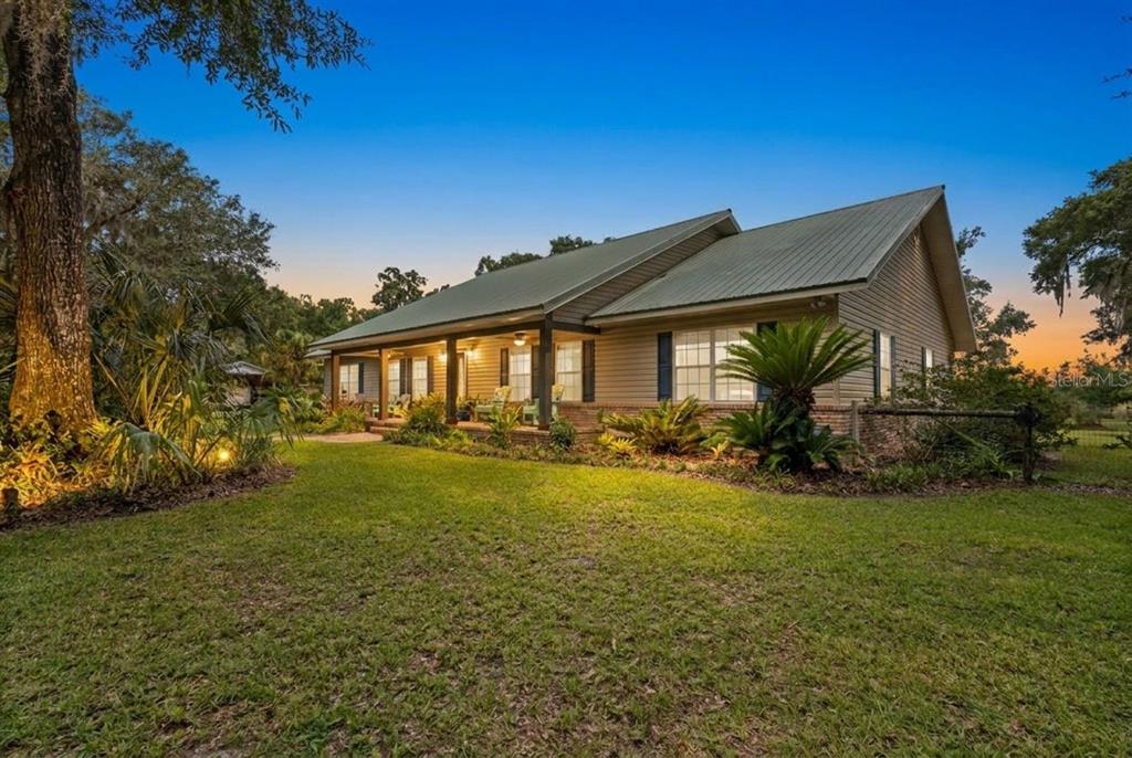 A single-story house with a metal roof and a covered front porch at twilight — 8851 NW 115TH STREET, CHIEFLAND, FL