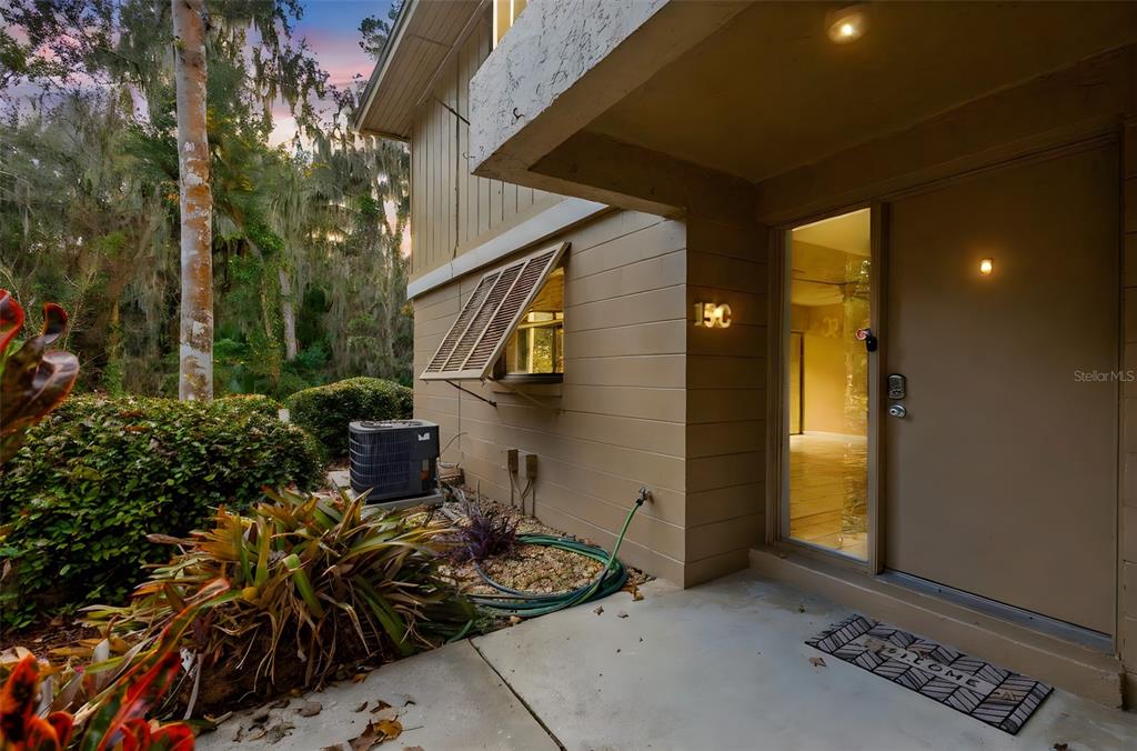 The exterior of a tan building features a front entrance, a window with shutters, and landscaping — 120 HIBISCUS WOODS COURT UNIT 15C, DELTONA, FL