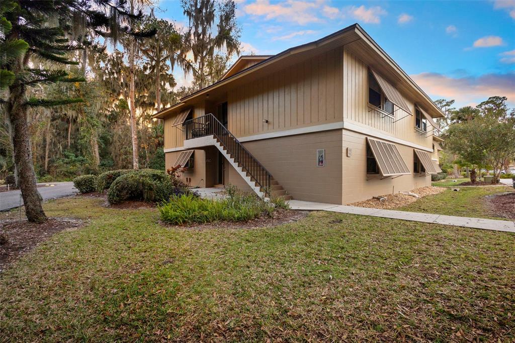 A two-story building with tan siding, metal window awnings, and an exterior staircase — 120 HIBISCUS WOODS COURT UNIT 15C, DELTONA, FL