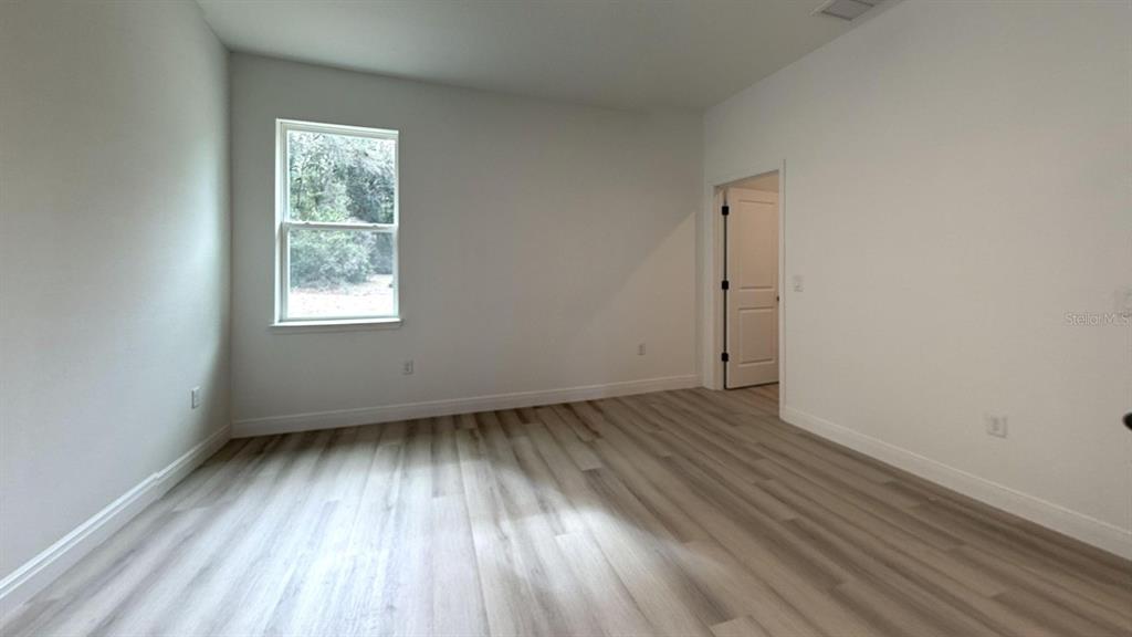 An empty bedroom features light-colored wood-look flooring, white walls, and a single window — 8839 N CITRUS SPRINGS BOULEVARD, CITRUS SPRINGS, FL