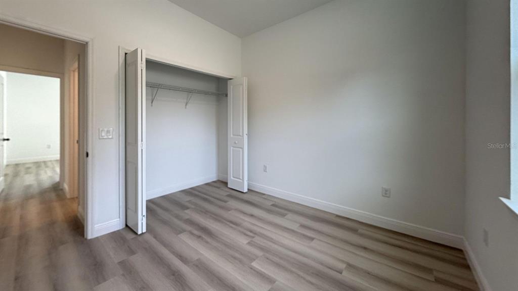 An empty bedroom features light-colored wood-look flooring, white walls, and a closet with bifold doors — 8839 N CITRUS SPRINGS BOULEVARD, CITRUS SPRINGS, FL