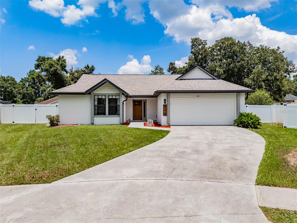 A single-story white house with a two-car garage and a concrete driveway — 304 SCARLET OAK COURT, SEFFNER, FL