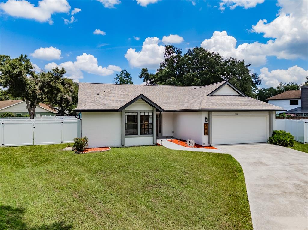 A white single-story house with a two-car garage and a front lawn under a blue sky — 304 SCARLET OAK COURT, SEFFNER, FL