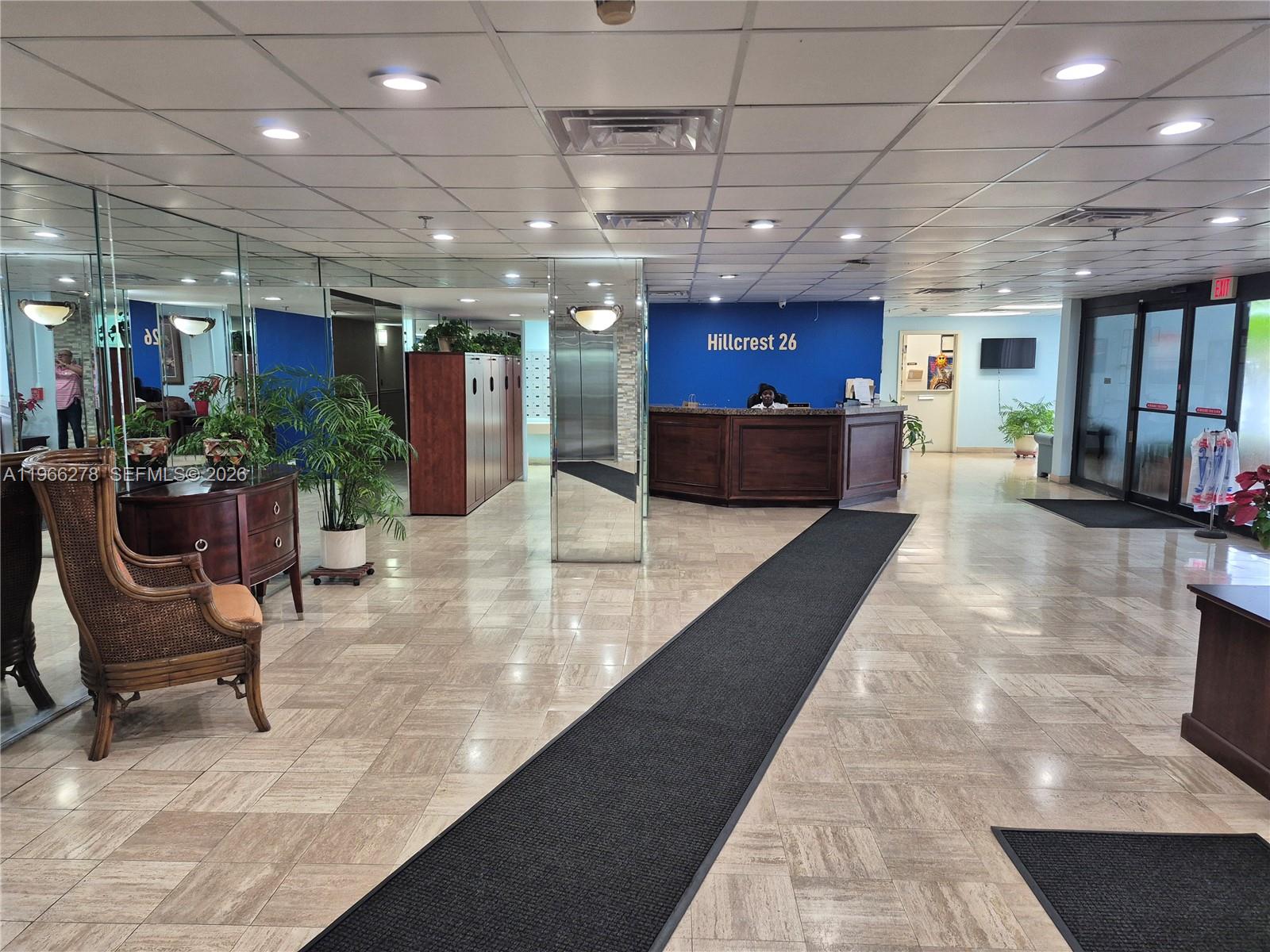 A lobby features a reception desk, tiled floors, a long runner rug, and mirrored walls — 4001 Hillcrest Dr # 416, Hollywood FL 33021, HOLLYWOOD, FL