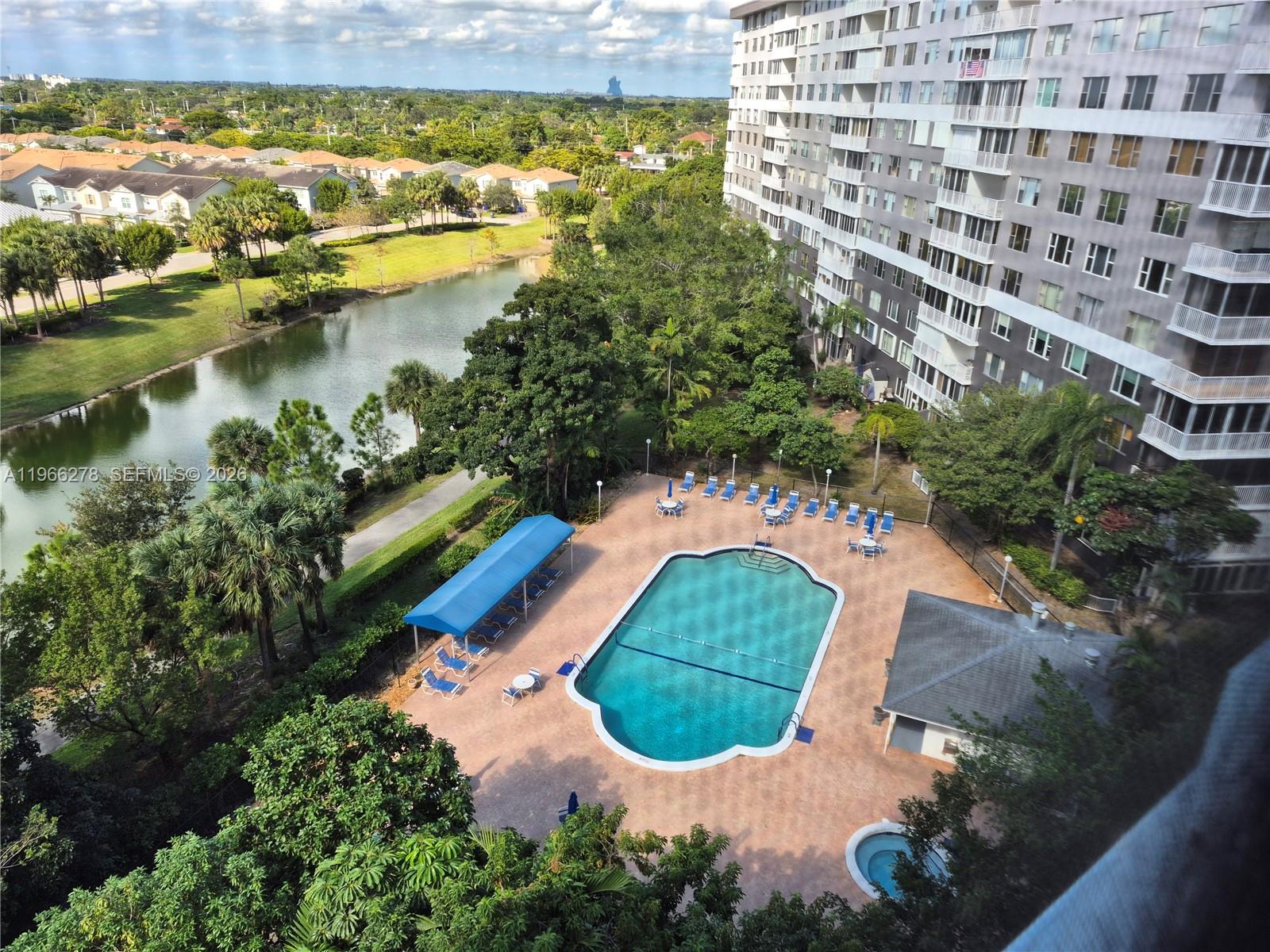 An elevated view shows a swimming pool, a small building, and a lake near apartments — 4001 Hillcrest Dr # 416, Hollywood FL 33021, HOLLYWOOD, FL