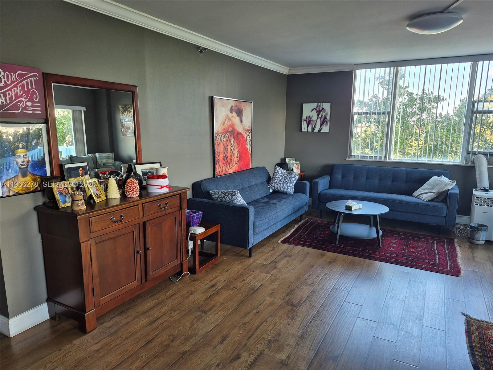 A living room features two blue sofas, a wooden sideboard, and dark wood flooring — 4001 Hillcrest Dr # 416, Hollywood FL 33021, HOLLYWOOD, FL