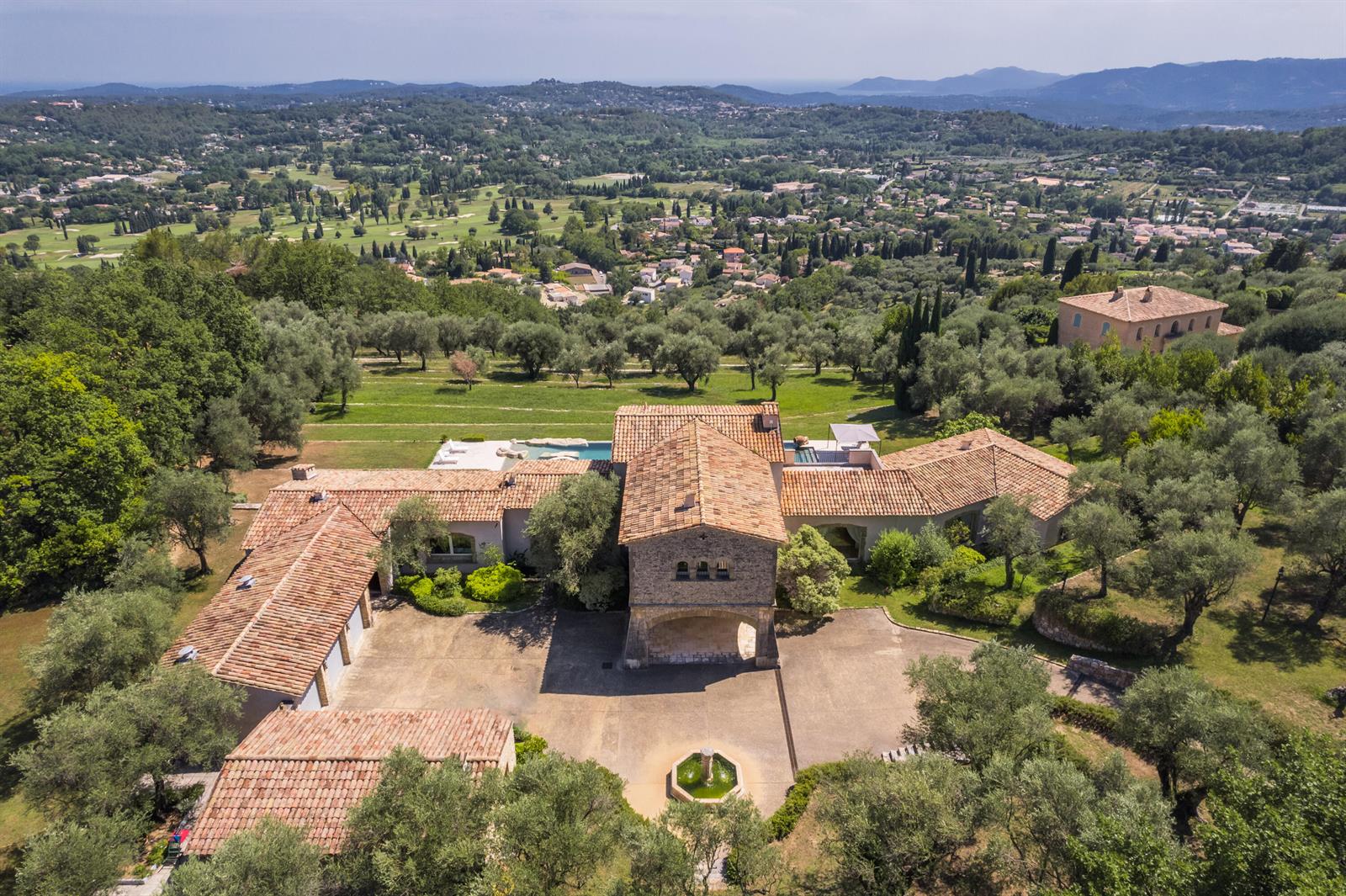 An aerial view shows a stone villa with a tiled roof, courtyard, and swimming pool — 20 Chemin De Bellevue, FL