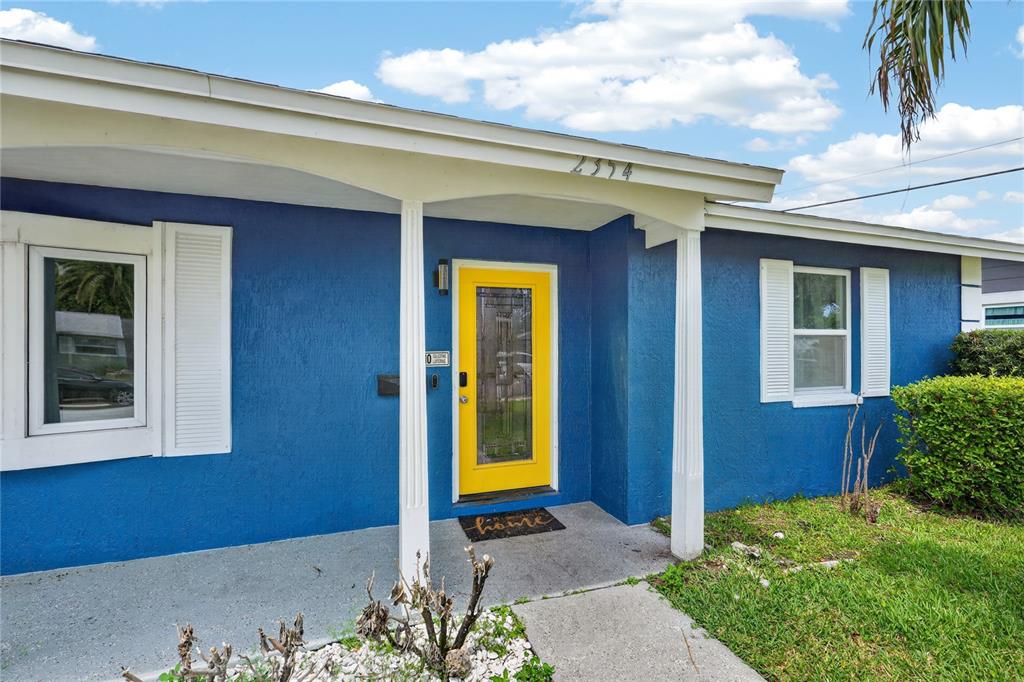 A blue house exterior features a bright yellow front door and white porch columns — 2354 GREEN STREET, SOUTH DAYTONA, FL