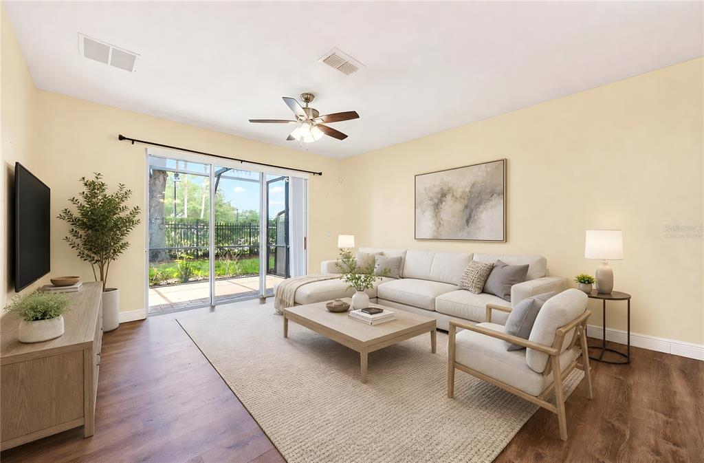 A living room features light yellow walls, wood-look flooring, a sectional sofa, and sliding glass doors — 10329 BELFRY CIRCLE, ORLANDO, FL