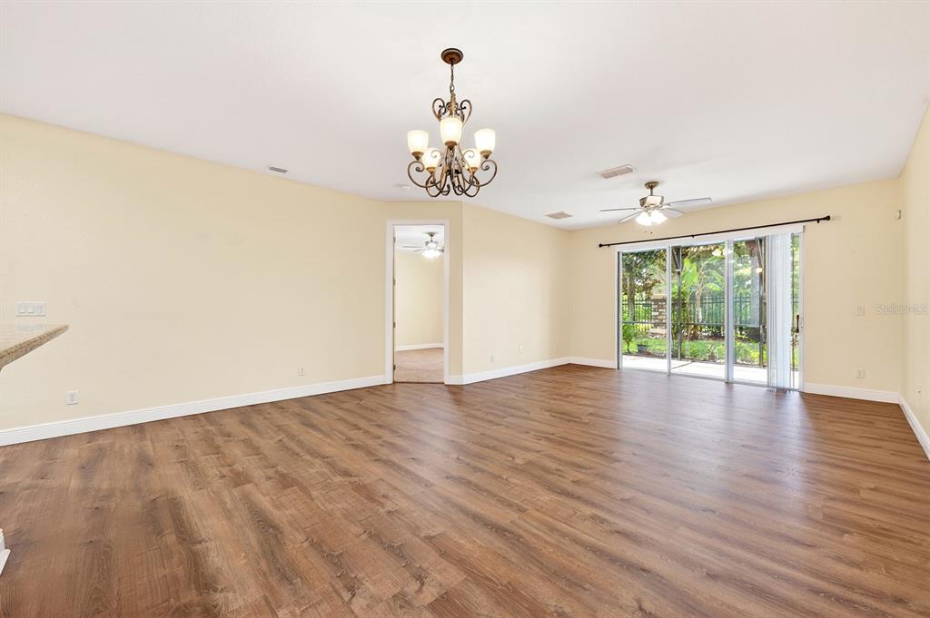 A spacious living room features wood-look flooring, a chandelier, a ceiling fan, and sliding doors — 10329 BELFRY CIRCLE, ORLANDO, FL