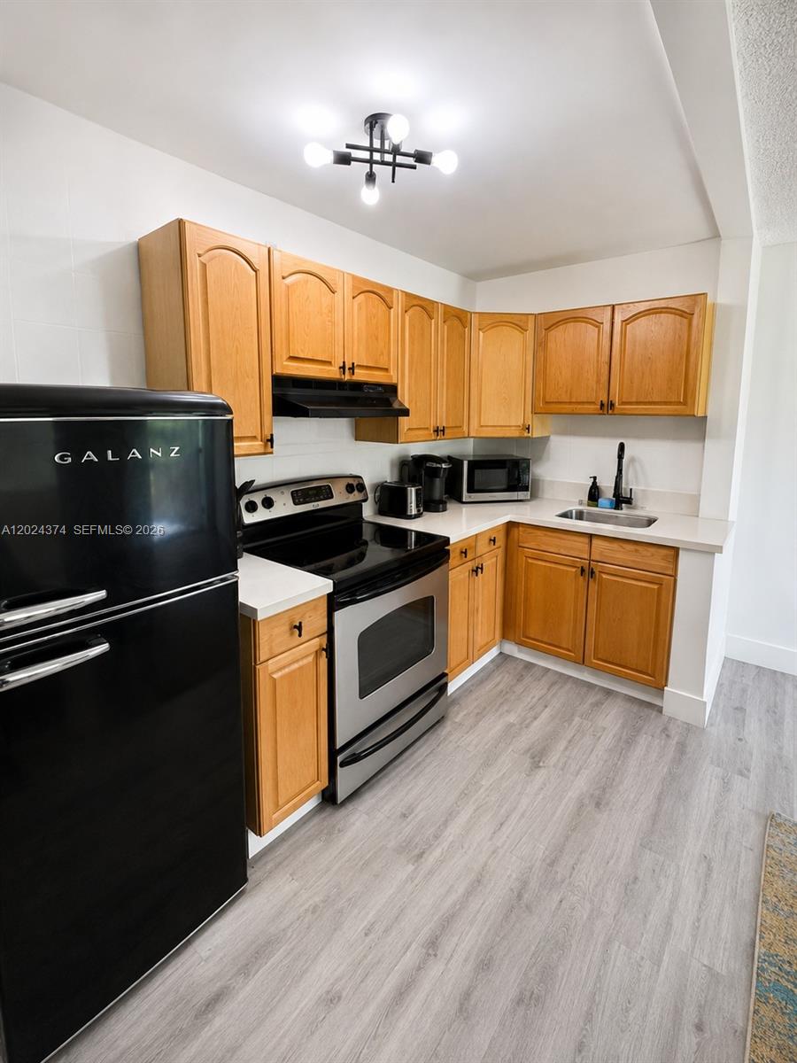 A kitchen features light wood cabinets, stainless steel appliances, a black refrigerator, and light flooring — 3210 Canal Dr # 6, Pompano Beach FL 33062, POMPANO BEACH, FL
