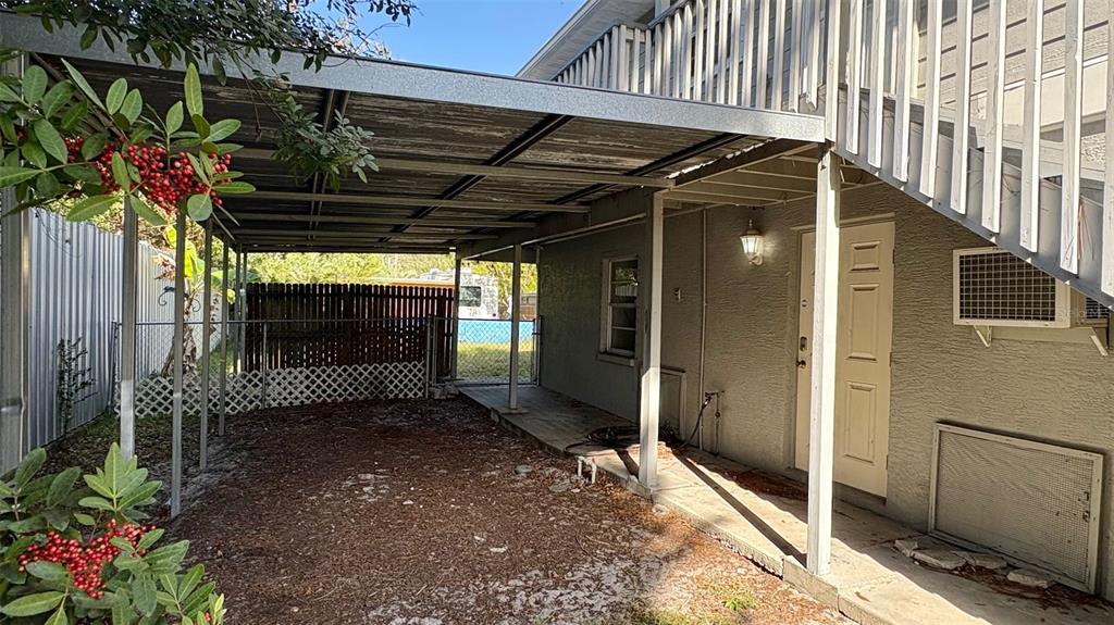 A covered carport area sits beside a two-story building with a white staircase — 7815 BUTLER AVENUE, HUDSON, FL