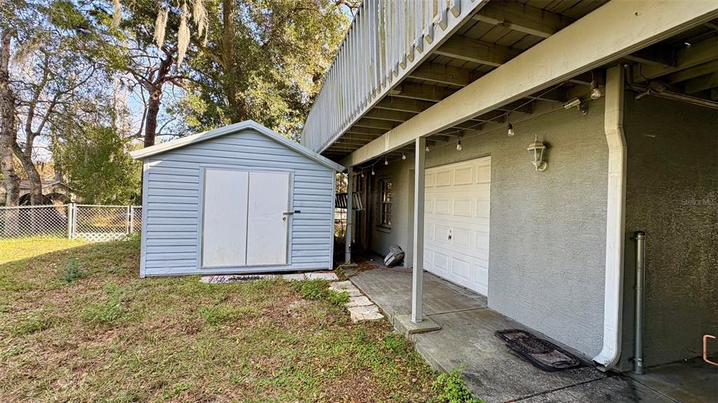 A light blue storage shed sits on the grass next to a house with a garage — 7815 BUTLER AVENUE, HUDSON, FL