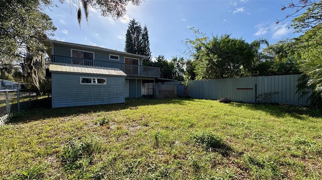 A two-story house with a balcony and a metal fence in a grassy backyard — 7815 BUTLER AVENUE, HUDSON, FL