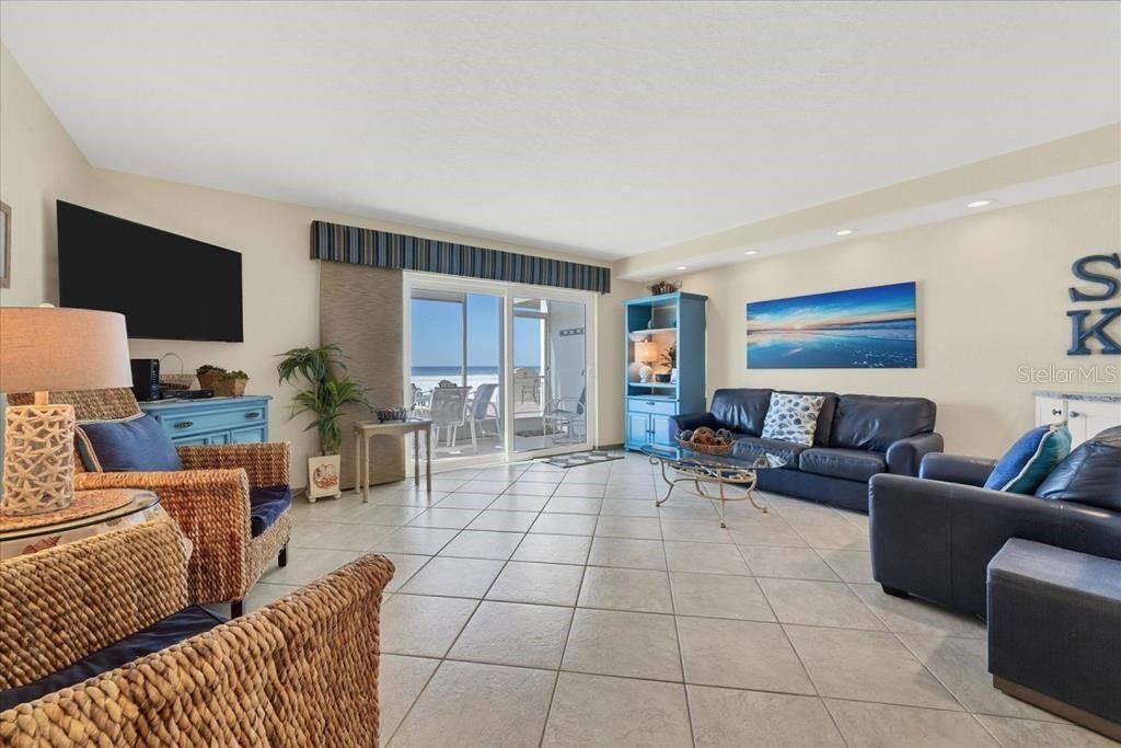 A living room features tile flooring, wicker chairs, a dark sofa, and a balcony view — 6154 MIDNIGHT PASS ROAD UNIT 102, SARASOTA, FL