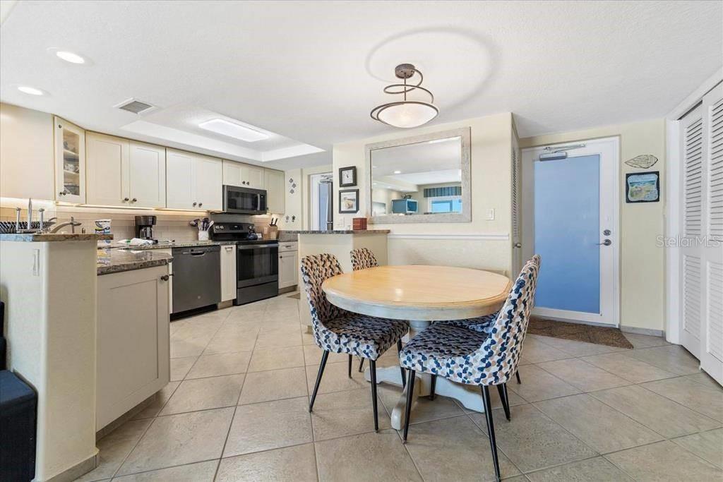 A kitchen with light cabinets and a dining area featuring a round table and chairs — 6154 MIDNIGHT PASS ROAD UNIT 102, SARASOTA, FL