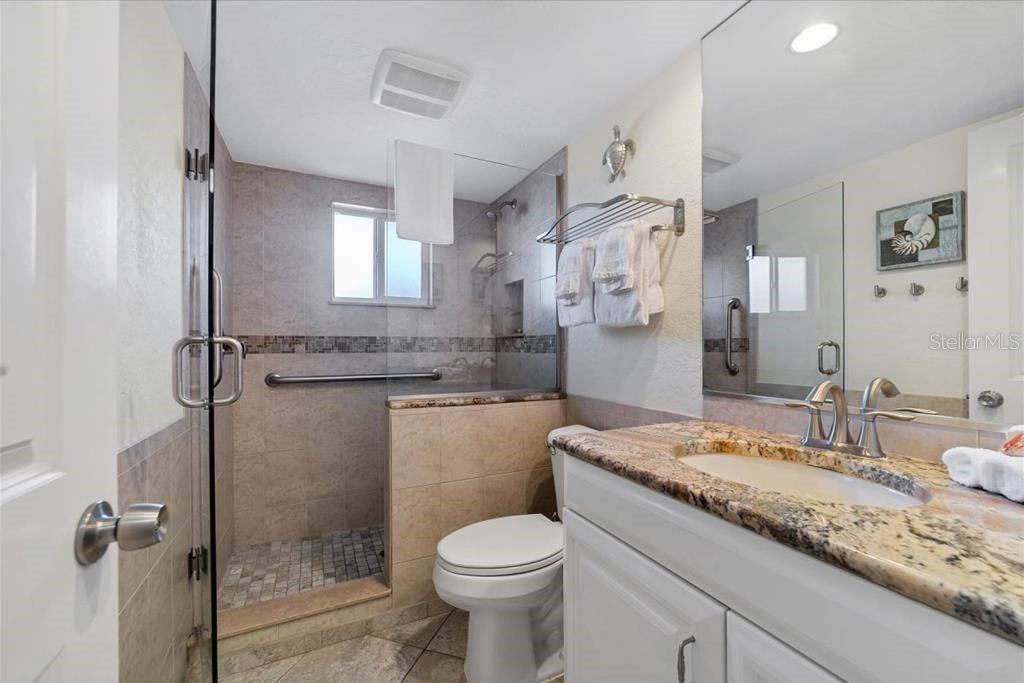 A bathroom features a walk-in shower with a glass door, a toilet, and a vanity — 6154 MIDNIGHT PASS ROAD UNIT 102, SARASOTA, FL