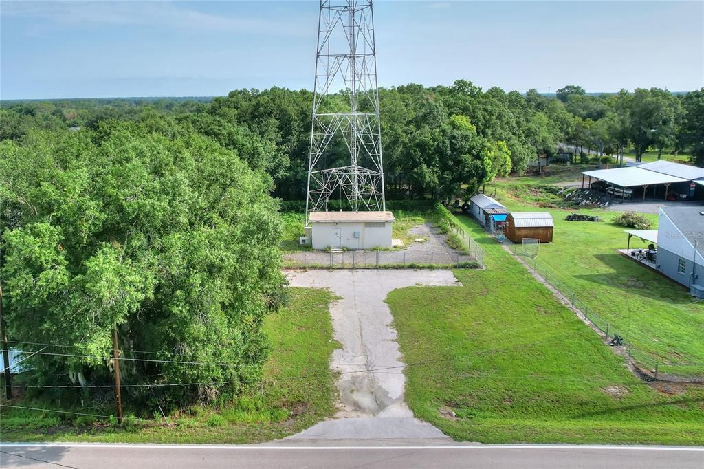 An aerial view shows a tall metal communications tower on a fenced concrete lot — 325 WILDER ROAD, LAKELAND, FL