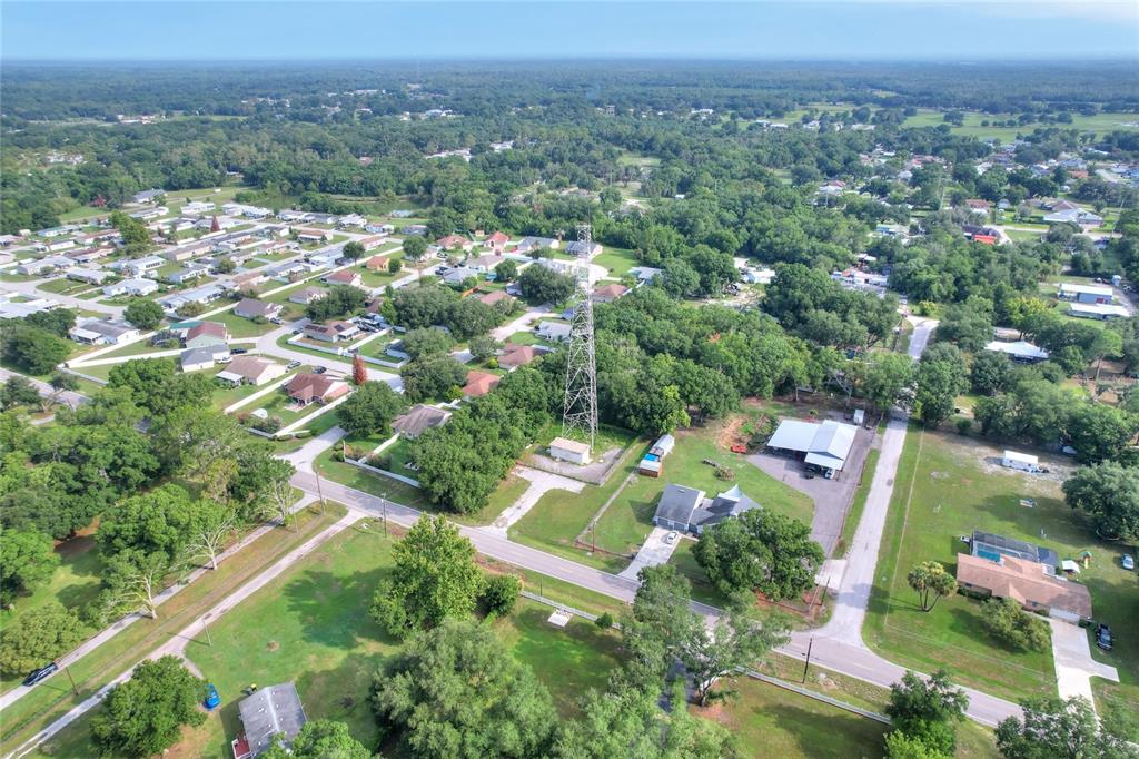 An aerial view shows a residential neighborhood with a tall communication tower and surrounding trees — 325 WILDER ROAD, LAKELAND, FL