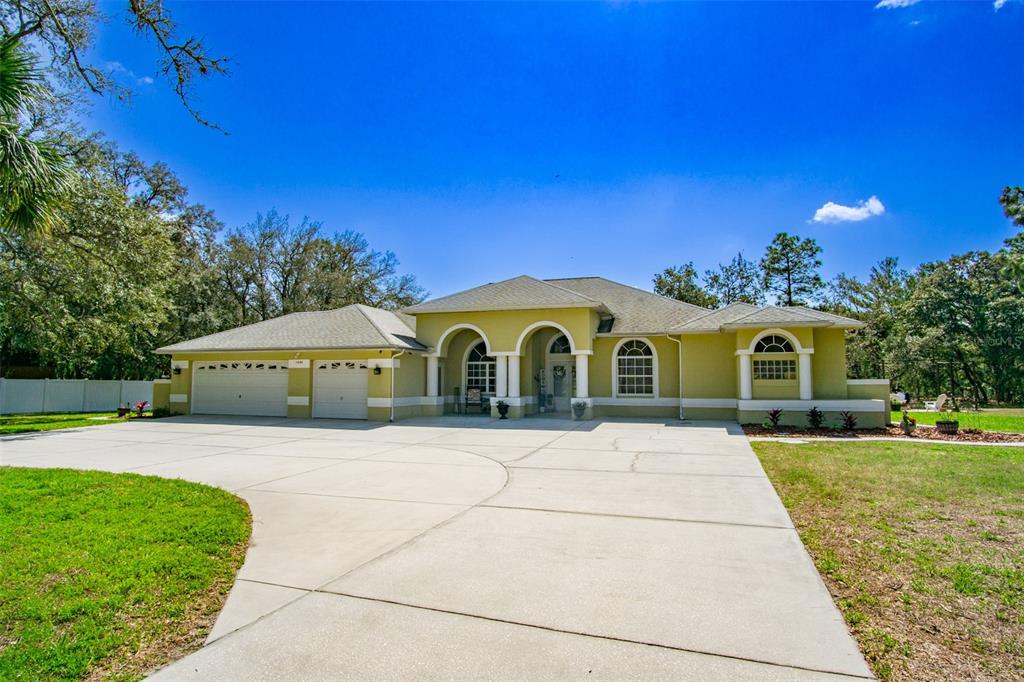 A single-story house with a light green exterior, a three-car garage, and a concrete driveway — 11092 MIRAGE AVENUE, WEEKI WACHEE, FL
