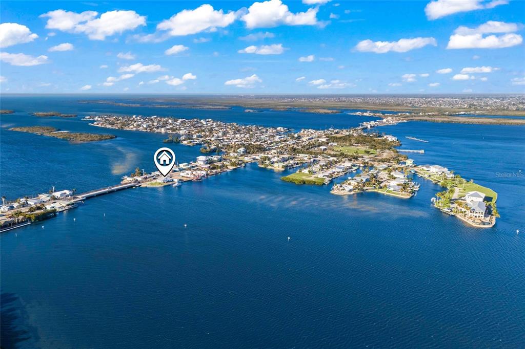 An aerial view shows a coastal town surrounded by water with a bridge connecting landmasses — 4767 PINE ISLAND ROAD NW, MATLACHA, FL