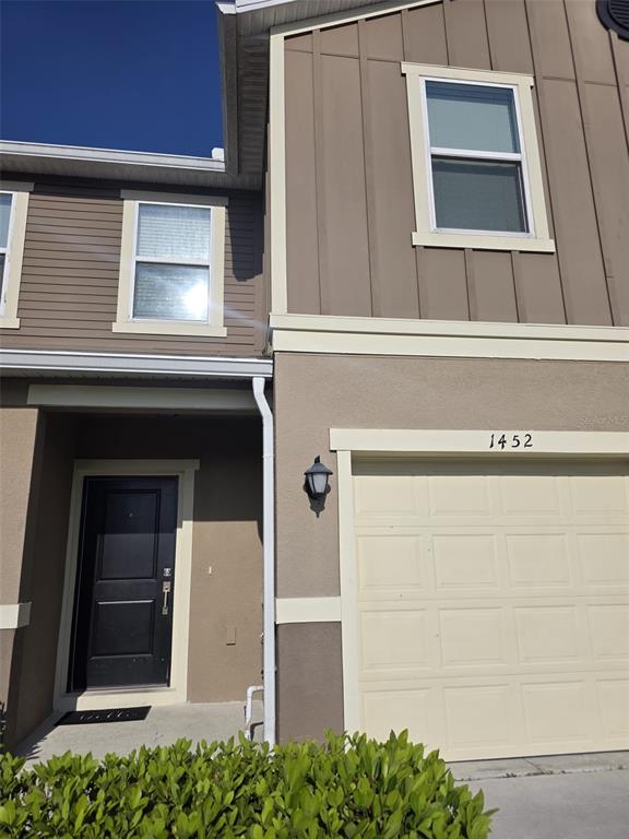 A two-story townhouse exterior features a black front door, a garage, and tan siding — 1452 MIRABELLA CIRCLE, DAVENPORT, FL