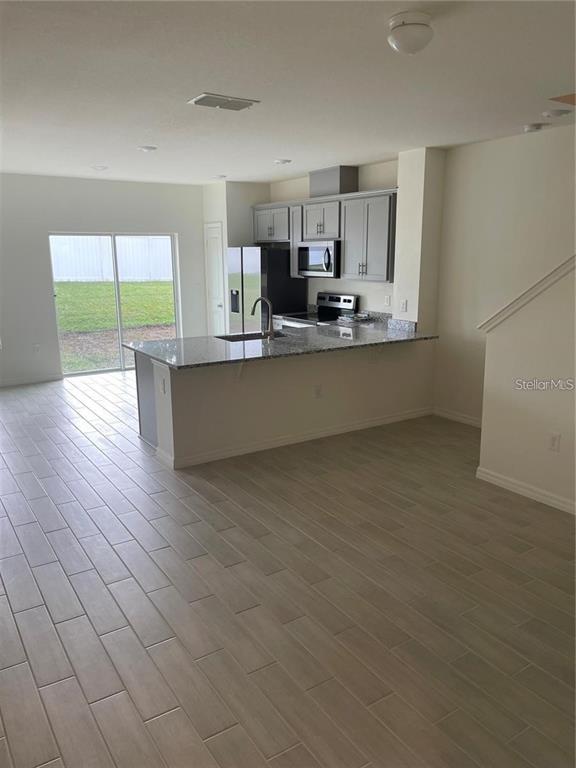 A kitchen with gray cabinets, granite countertops, and tile flooring opens to a backyard view — 1452 MIRABELLA CIRCLE, DAVENPORT, FL