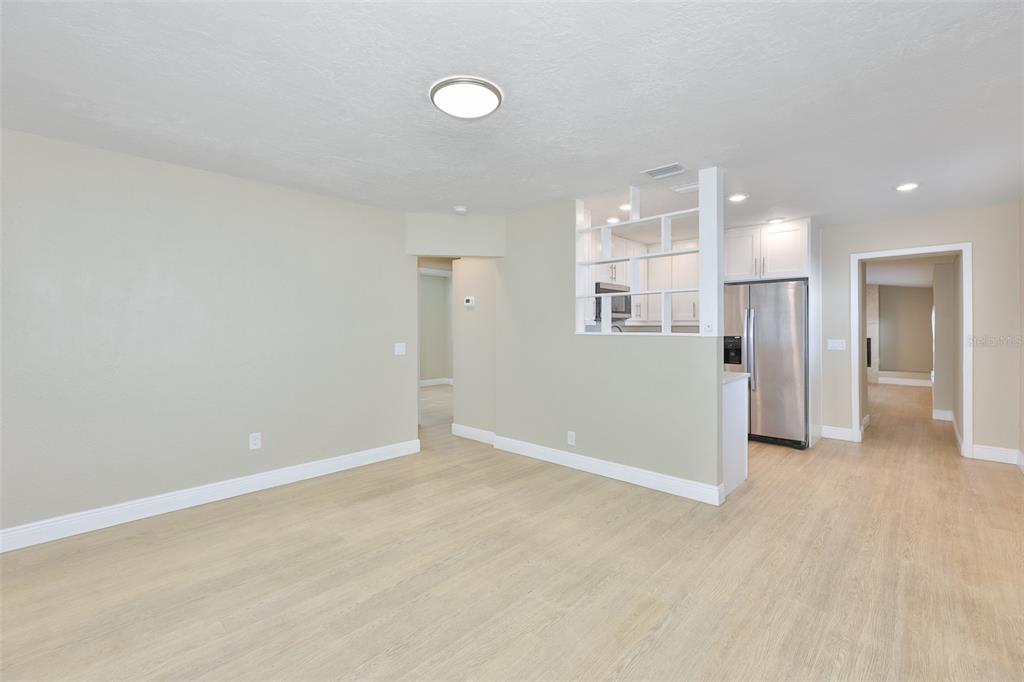 A bright, open-concept living area features light wood-look flooring and a white shelving partition — 2450 40TH AVENUE N, ST PETERSBURG, FL