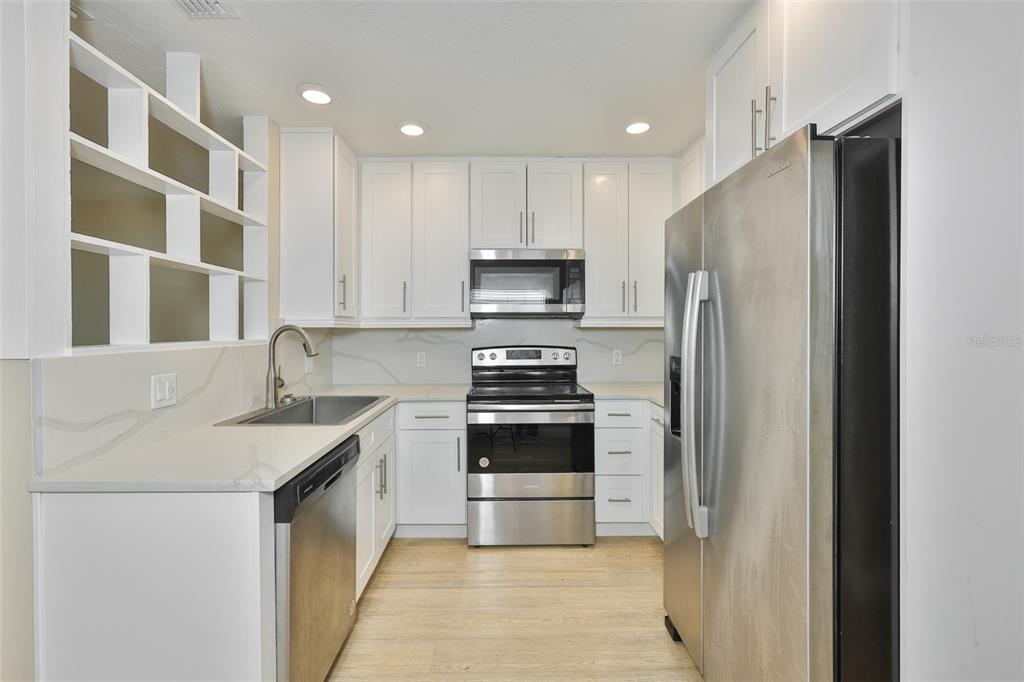 A kitchen features white cabinets, stainless steel appliances, and light-colored countertops — 2450 40TH AVENUE N, ST PETERSBURG, FL