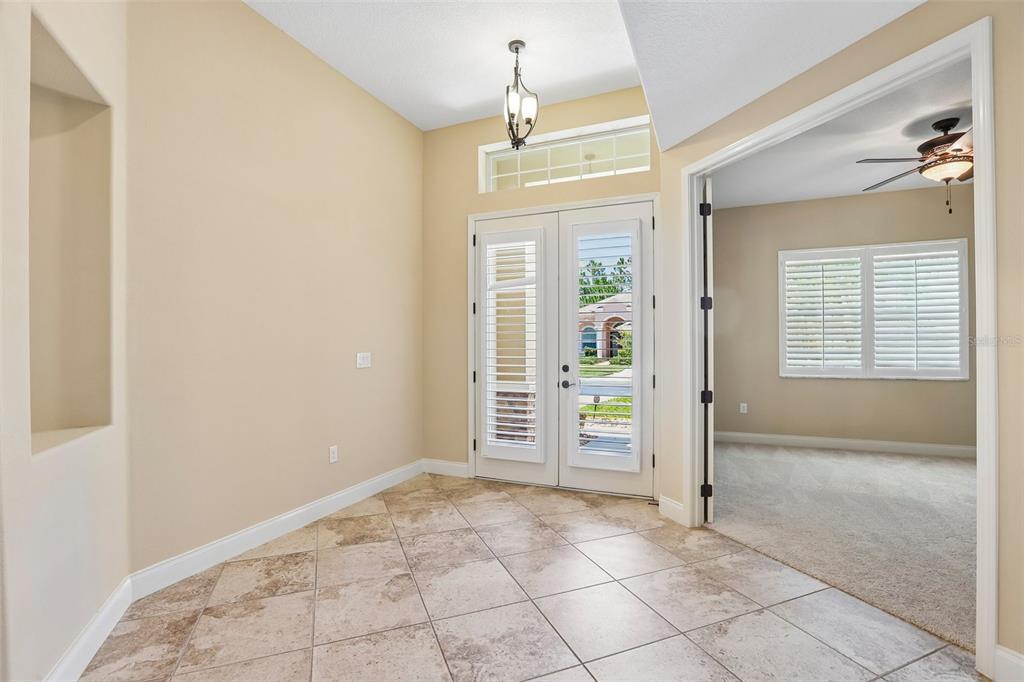 A tiled entryway features double glass doors, a recessed wall niche, and a light fixture — 27152 SORA BOULEVARD, WESLEY CHAPEL, FL
