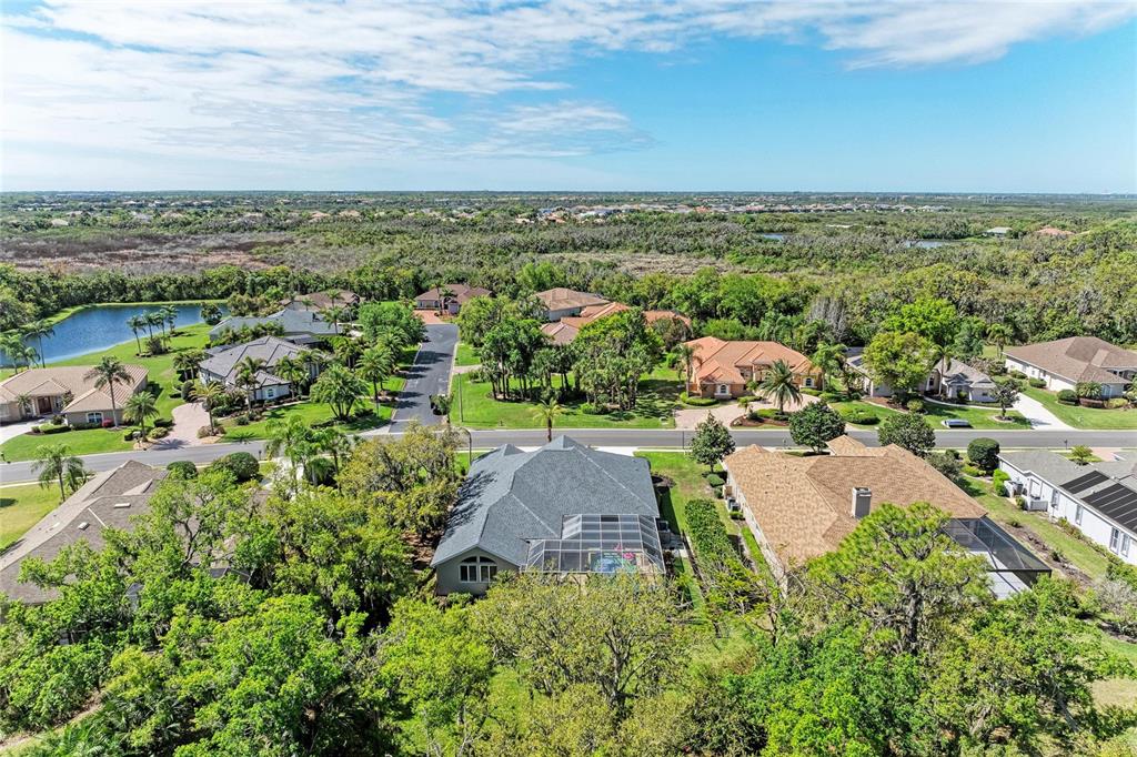 An aerial view shows several suburban houses with screened-in pools surrounded by lush green trees — 2337 LITTLE COUNTRY ROAD, PARRISH, FL