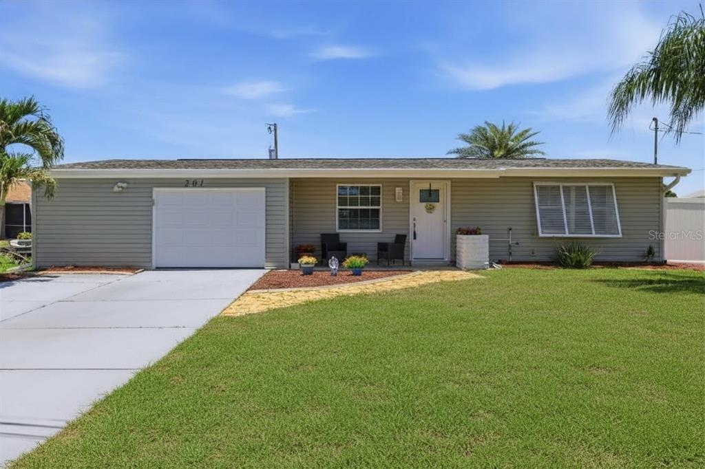 A single-story house with gray siding, a white garage door, and a front lawn — 201 E TARPON BLVD NW, PORT CHARLOTTE, FL
